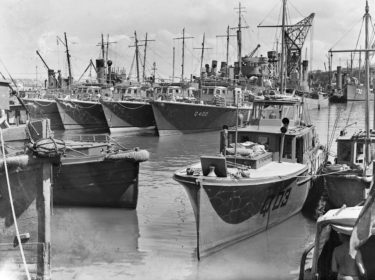 80th and 81st Fairmile Flotillas docked in Calliope Basin prior to their departure to the Solomon Islands. Twelve RNZN Fairmile patrol vessels and their crew were requested by Admiral Halsey (Commander of Allied Naval Forces in the South Pacific) for anti-submarine patrols around Tulagi, Russell Islands and Guadalcanal. Image: 2013.70.8390 80th and 81st Fairmile Flotillas docked in Calliope Basin prior to their departure to the Solomon Islands. Twelve RNZN Fairmile patrol vessels