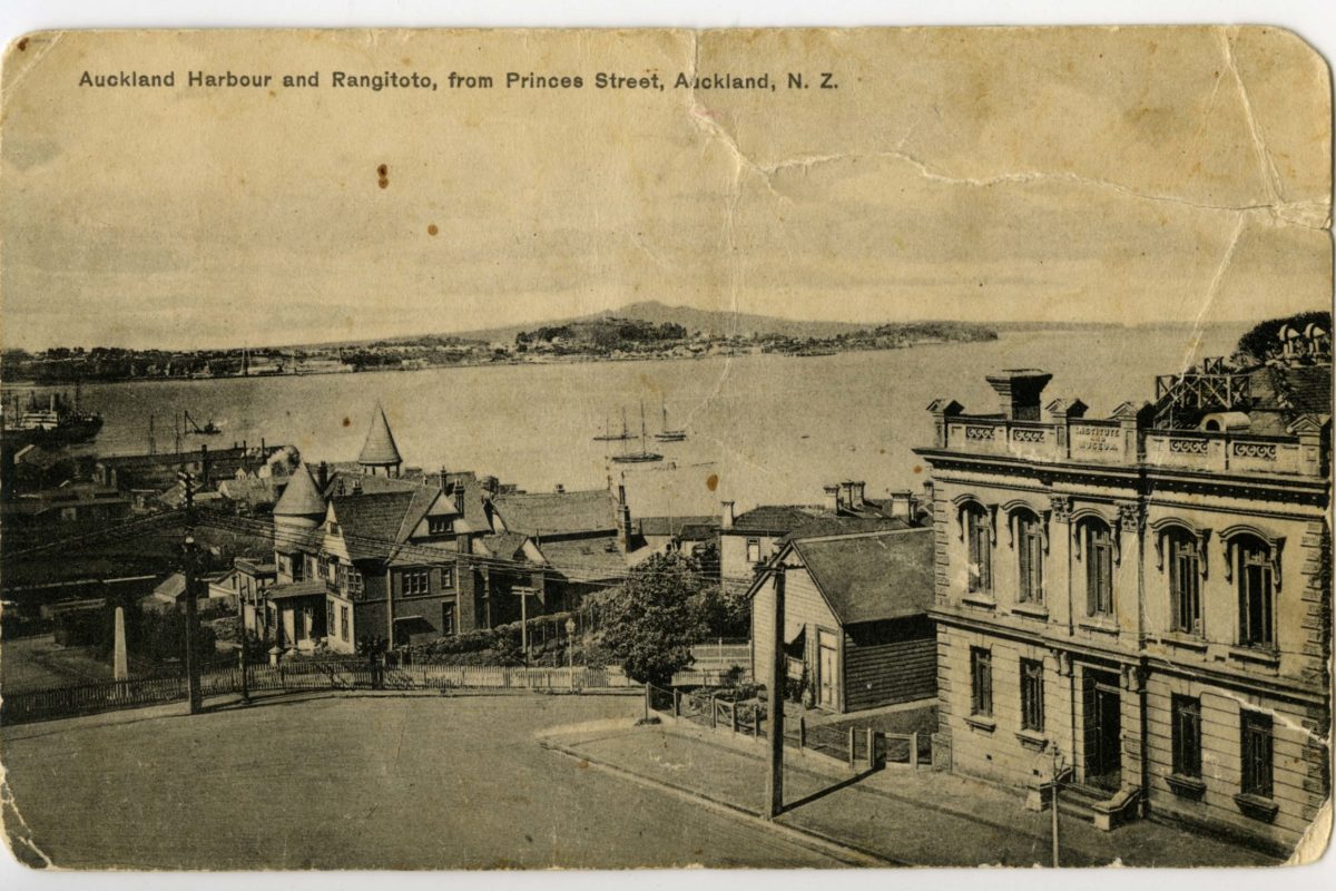 2018.145.1 i Postcard of 'Auckland Harbour and Rangitoto from Princes Street, Auckland, NZ.' showing Admiralty House in the centre as well as the old Auckland Museum building and caretakers house on Princes Street (right foreground).