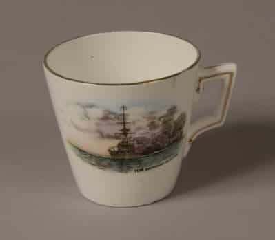 GEI-0023-Coffee-cup-e1422843334674 Demi Tasse white porcelain coffee cup with a gold rim around the top. Front of cup is decorated with a picture of a World War One battleship firing a broadside with painted words: ‘H.M Battleship in action’.